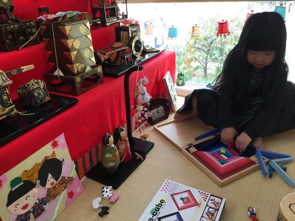 ひな人形の横で遊ぶ子供